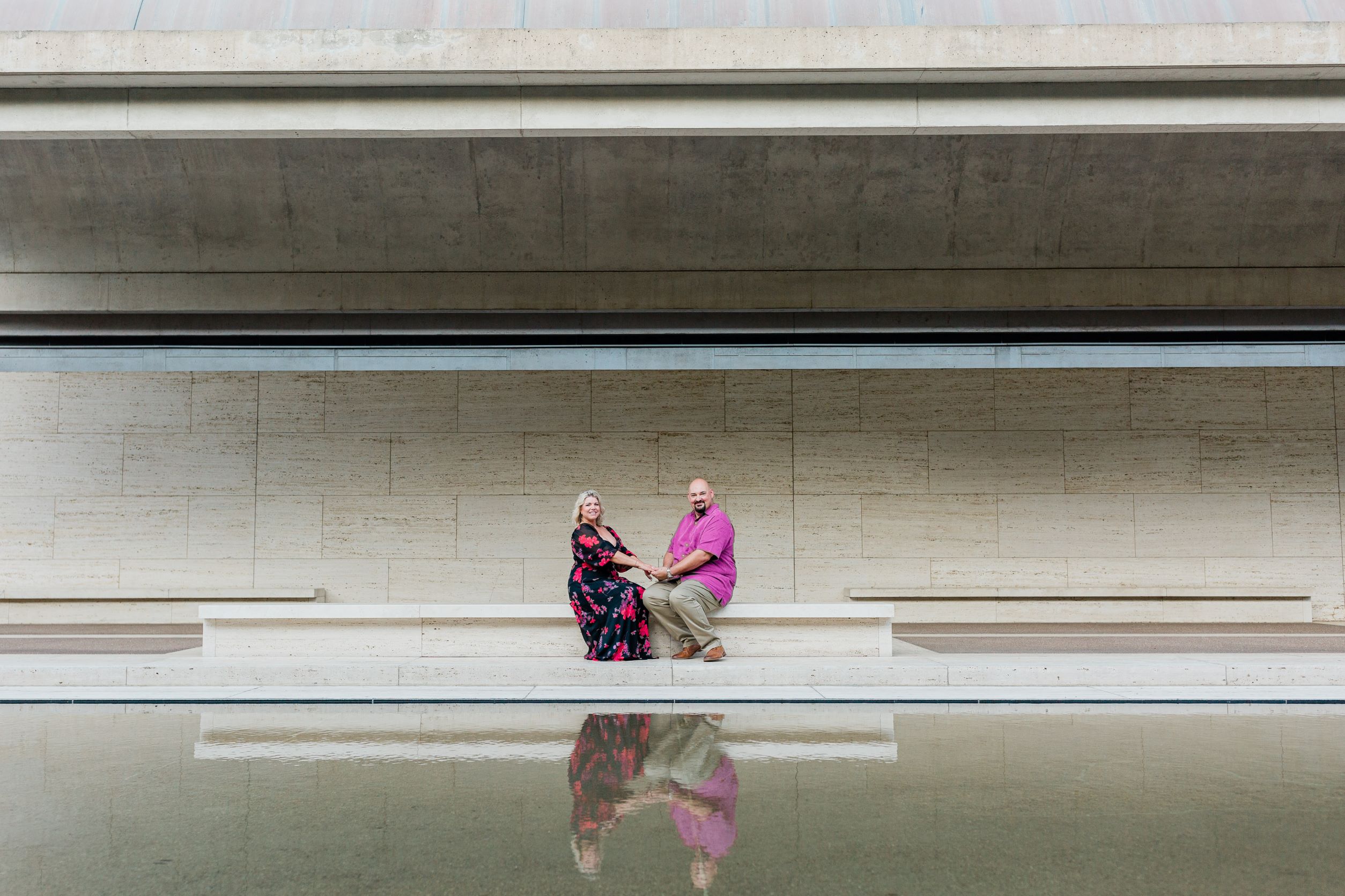 Monica and Tim sitting at the Kimbell Art Museum holding hands